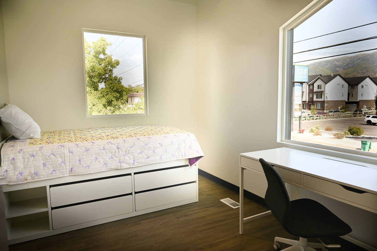 A student bedroom with a bed, desk, and natural light